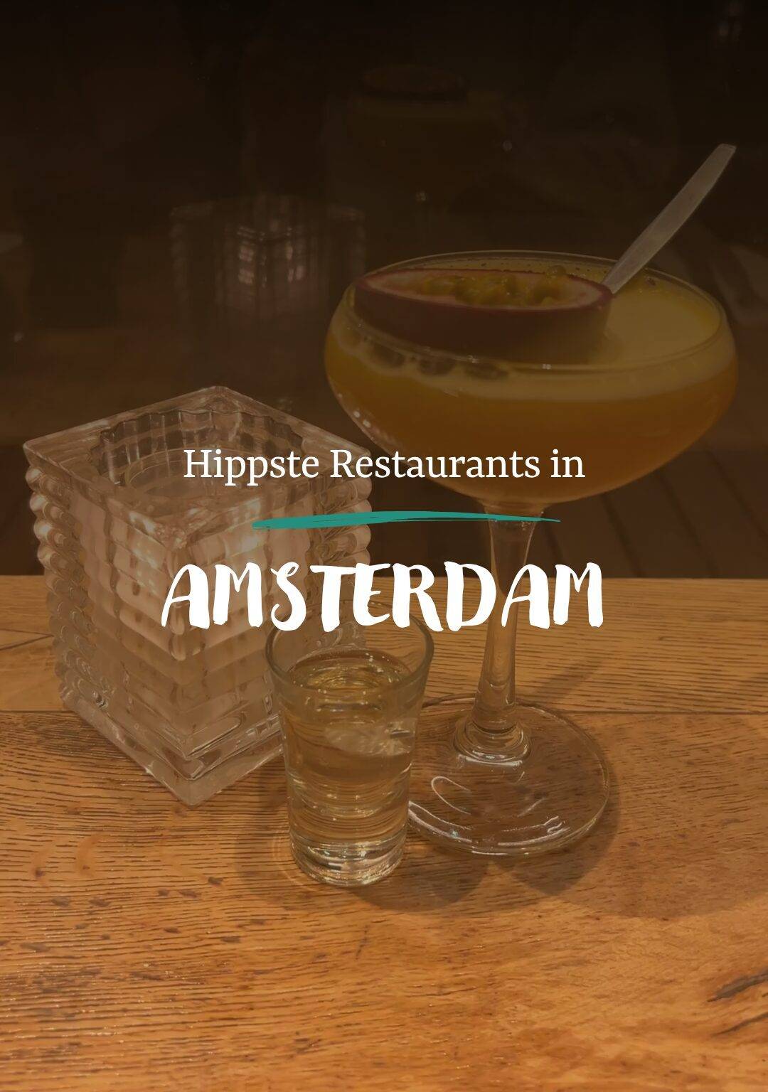 EIn Cocktail steht auf einem Holztisch, davor die Überschrift "Hippste Restaurants in Amsterdam".