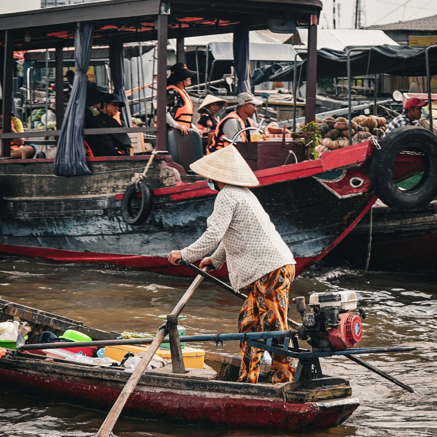 Eine Frau rudert stehend ein Boot auf dem schwimmenden Markt in Can Tho.