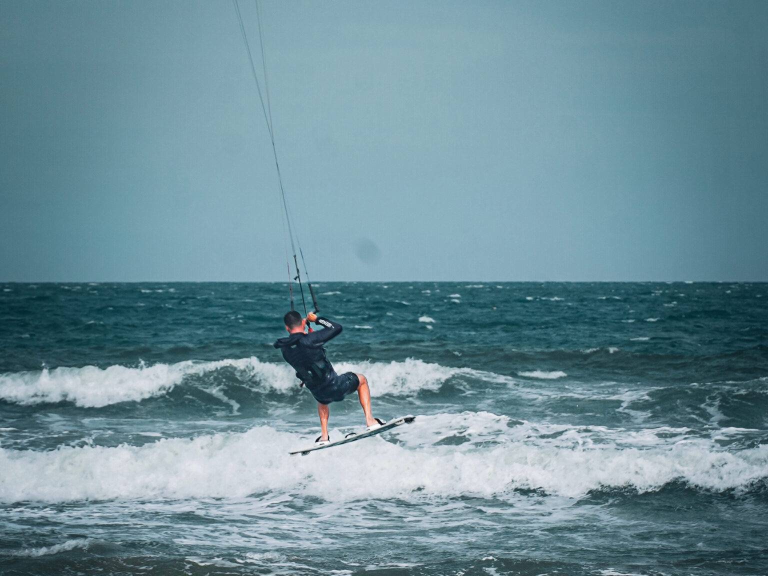 Ein Kitesurfer in der Luft bei einem Trick.