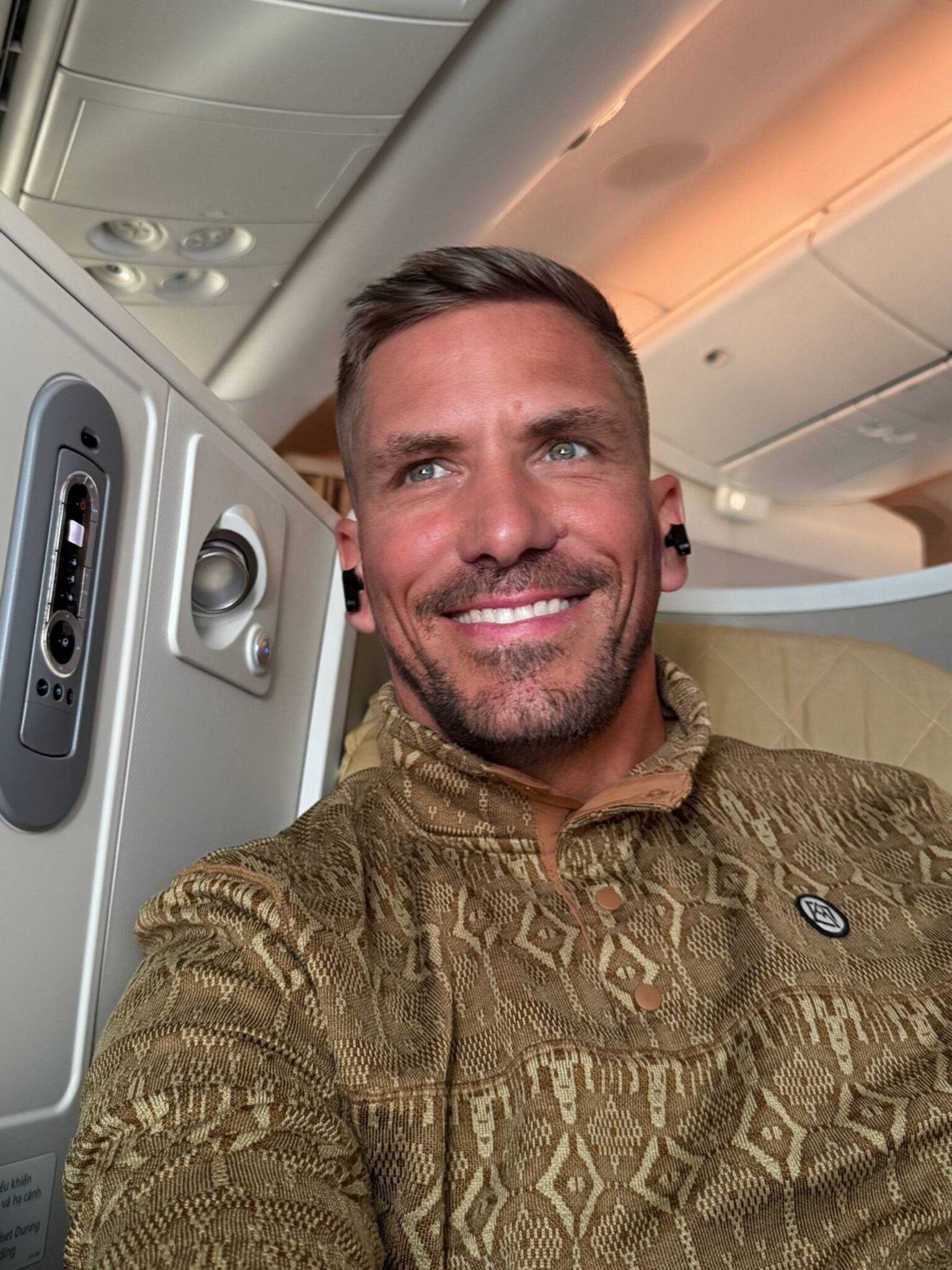 Daniel sitzt grinsend auf seinem Sitz in der Business Class von Vietnam Airlines.