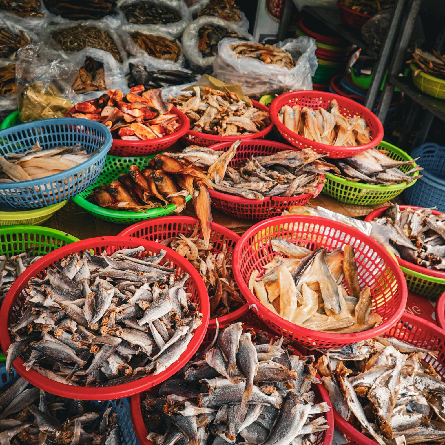 Straßenstand auf dem Markt von Cai Be mit Schalen voll mit Trockenfisch.