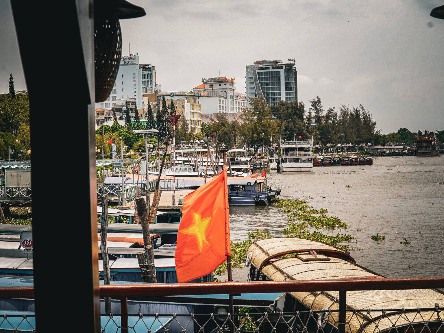 Der Hafen von Can Tho mit mehreren angebundenen Booten. Auf einem Boot weht die vietnamesische Flagge.