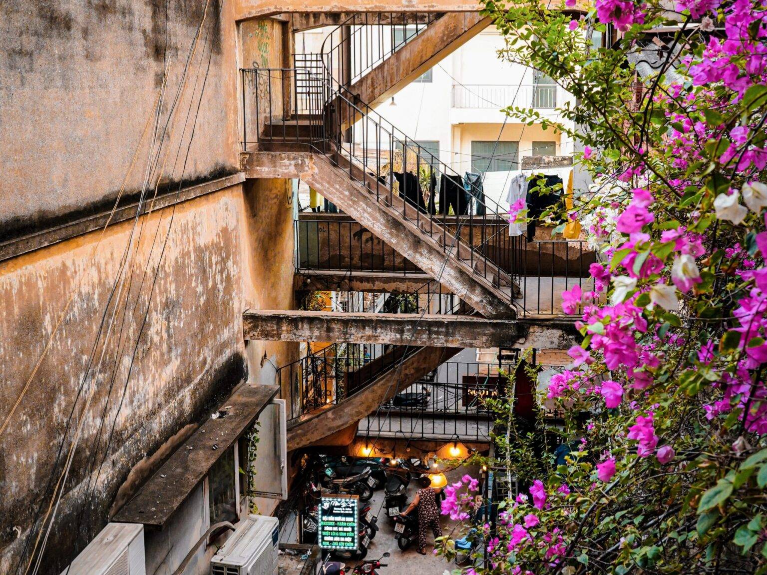 Die etwas heruntergekommene Fassade der 14 Ton That Dam Street in Ho Chi Minh City mit außen liegenden Treppen und einer blühenden Fassadenbegrünung rechts.