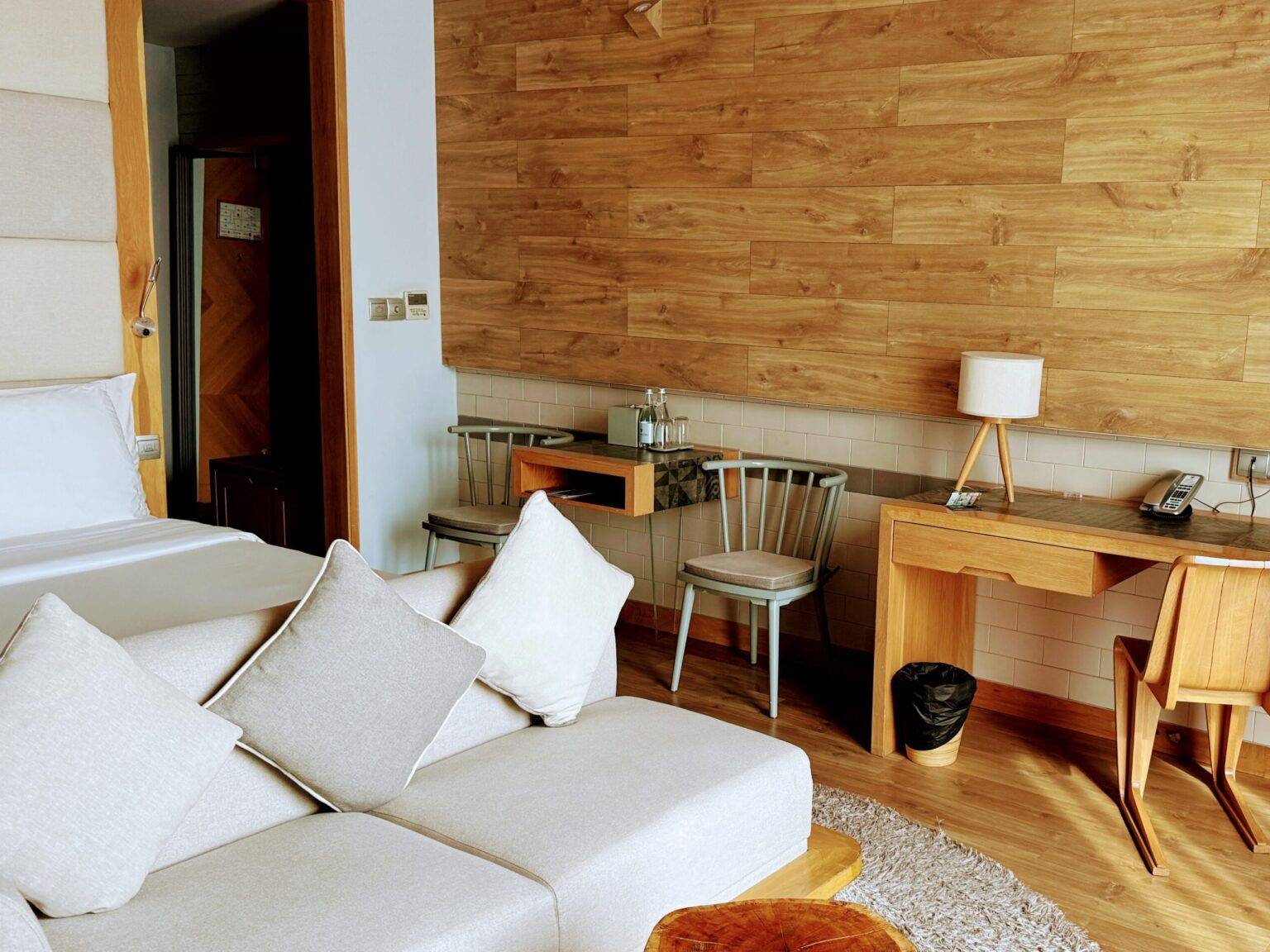 Ein Zimmer im Fusion Suites mit einer holzverkleideten Wand und einem hellen Sofa.