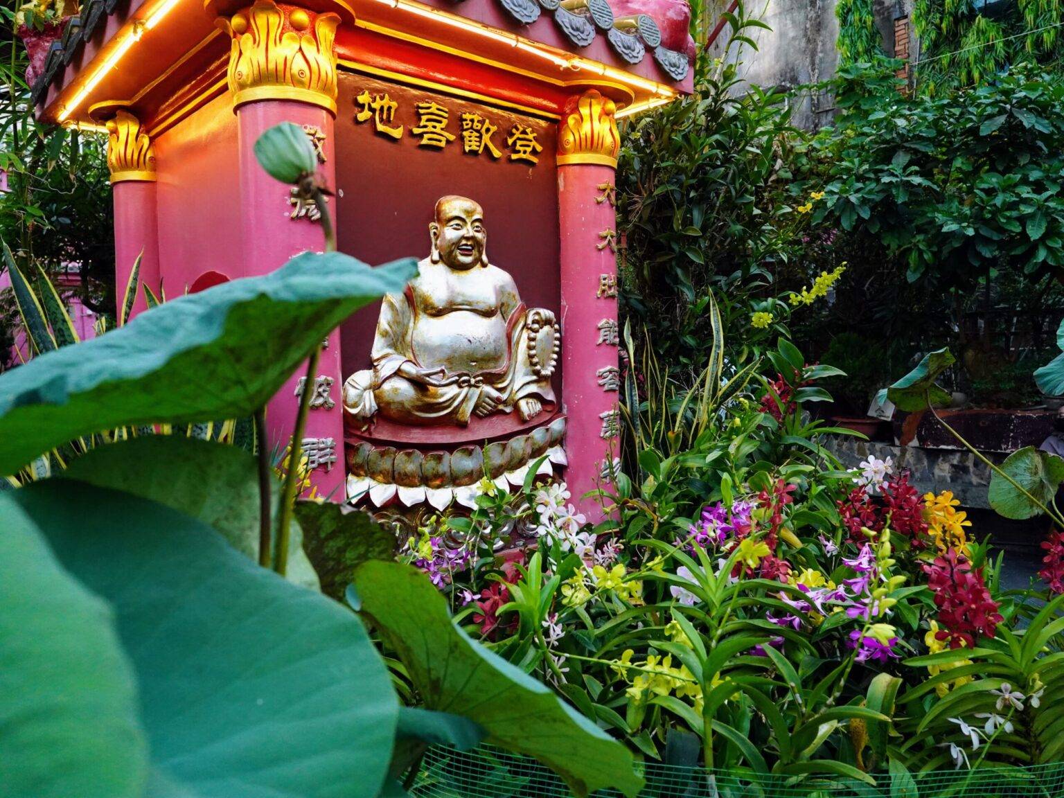 Ein Schrein mit Buddha umgeben von blühenden Pflanzen in der Jade Emperor Pagoda in Saigon.