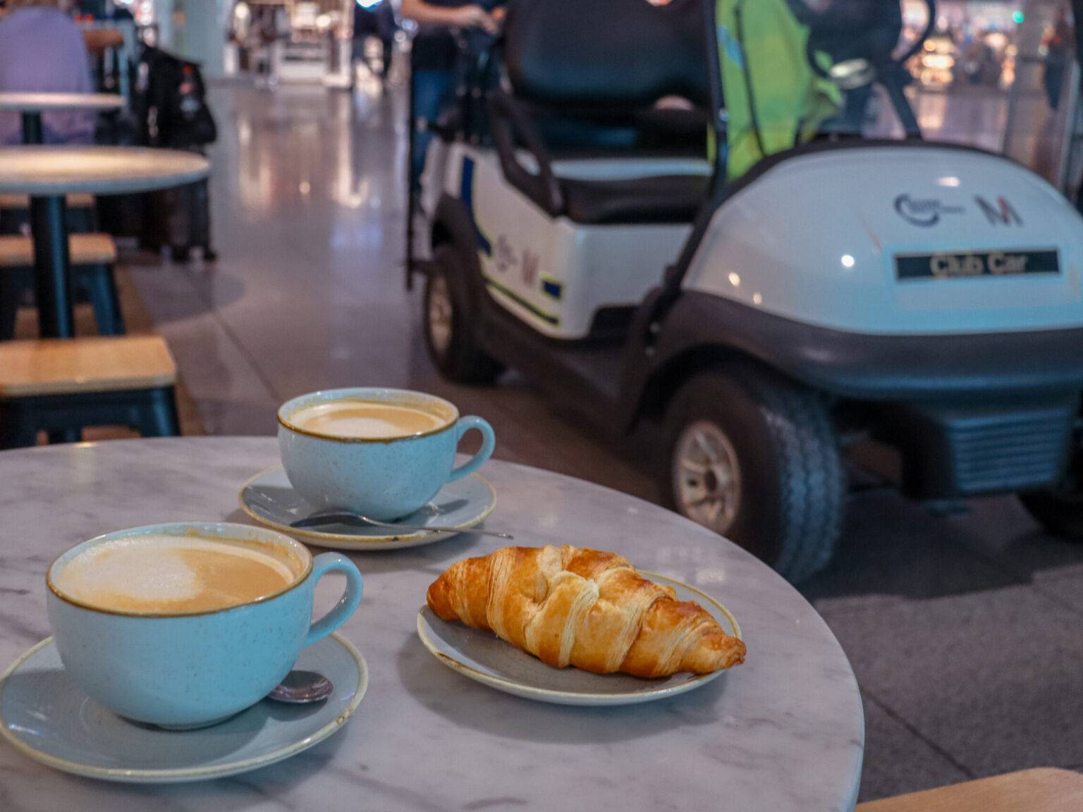 Ein Frühstück am Flughafen mit Kaffee und Croissant.