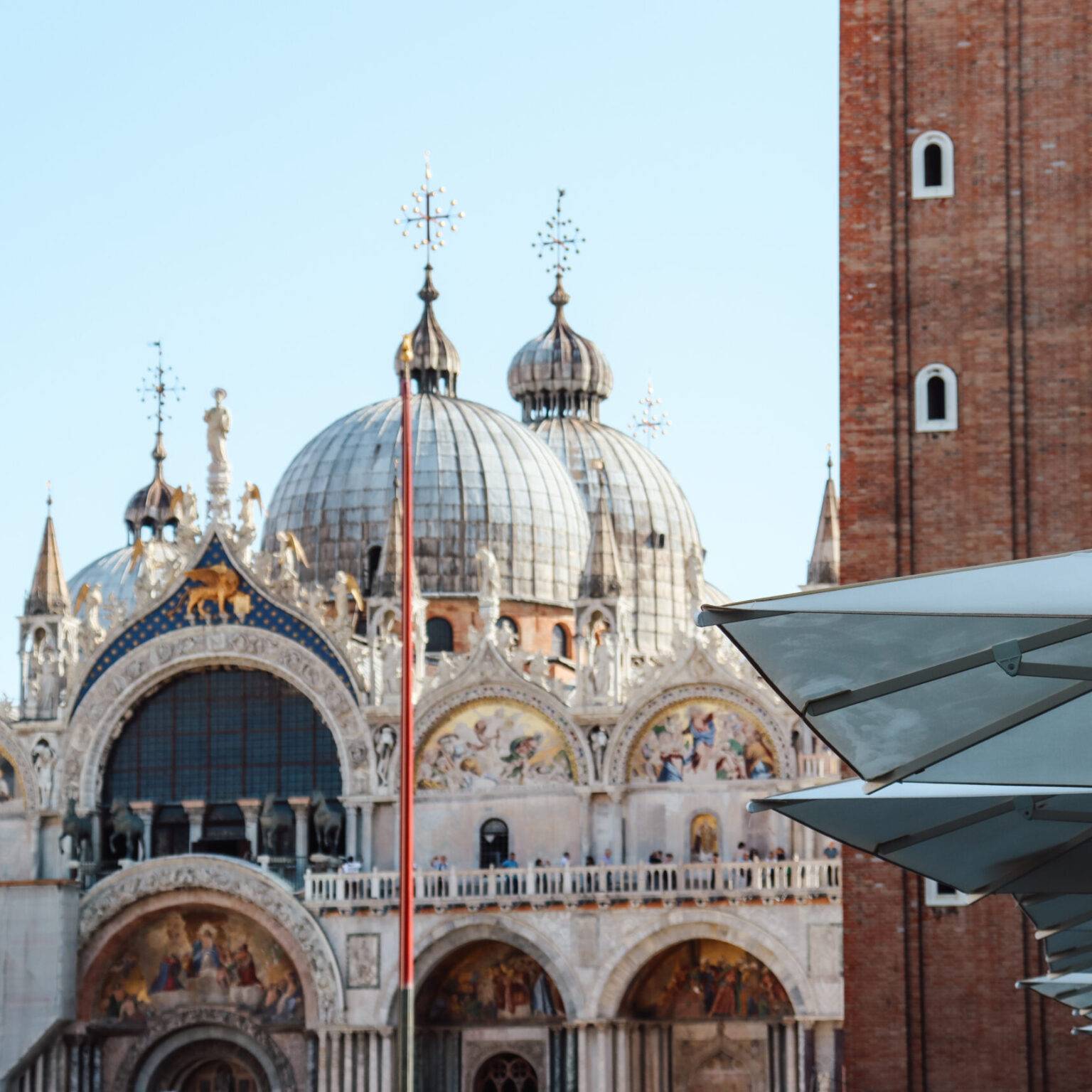 Fassade des Markusdoms in Venedig, hinter einem Café-Sonnenschirm auf dem Markusplatz.