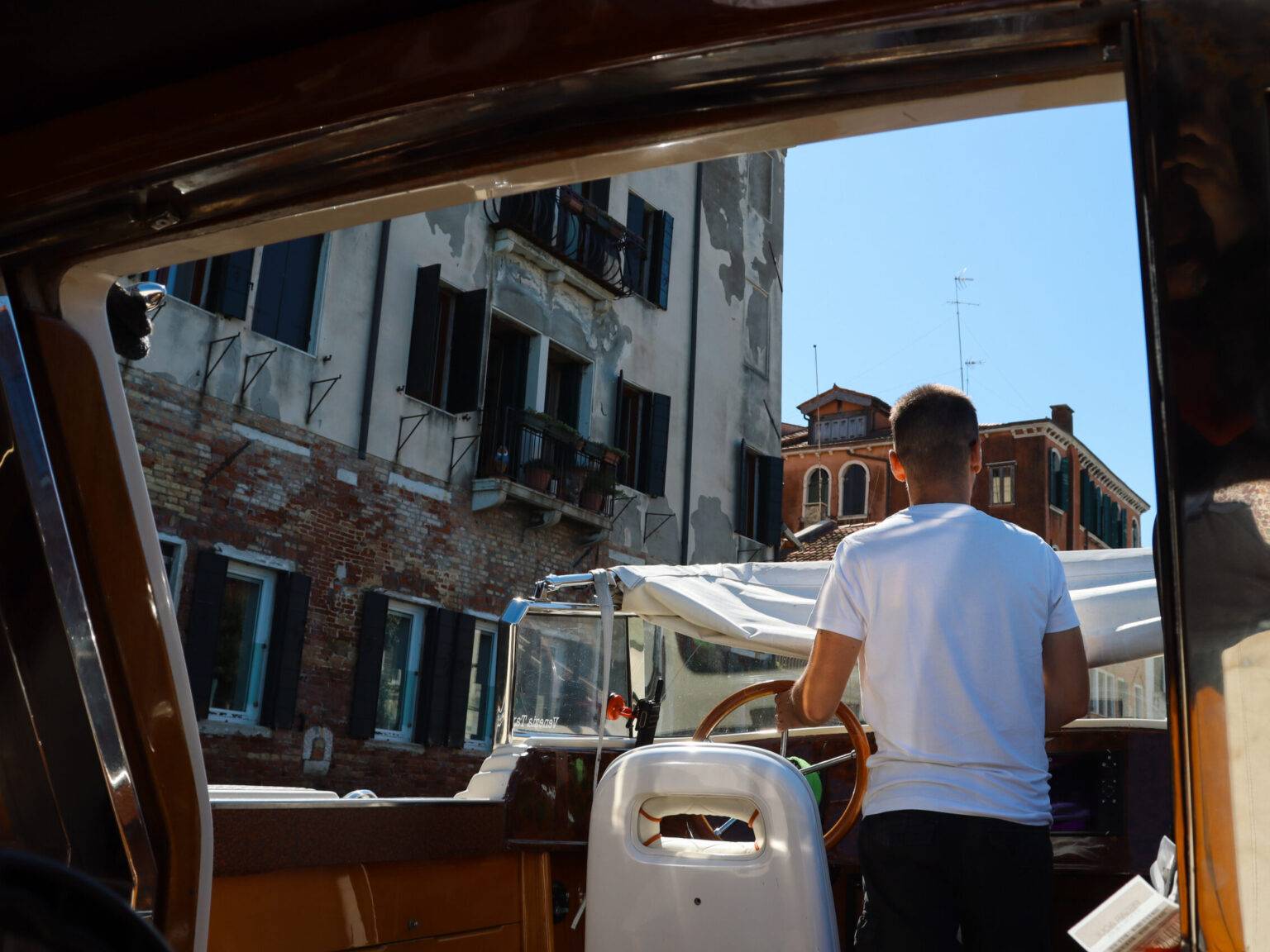 Der Kapitän eines privaten Wassertaxis von hinten, während er das Boot steuert.