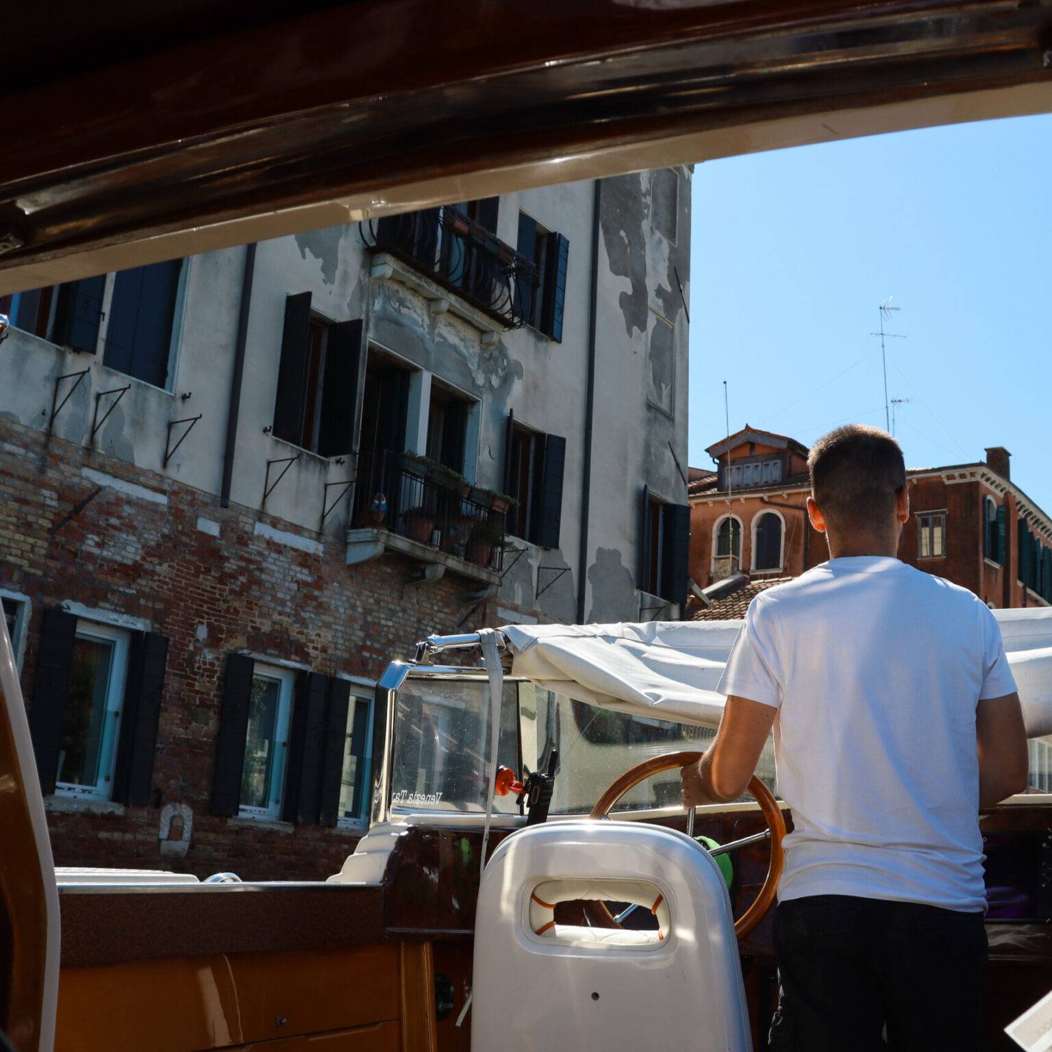 Der Kapitän eines privaten Wassertaxis von hinten, während er das Boot steuert.