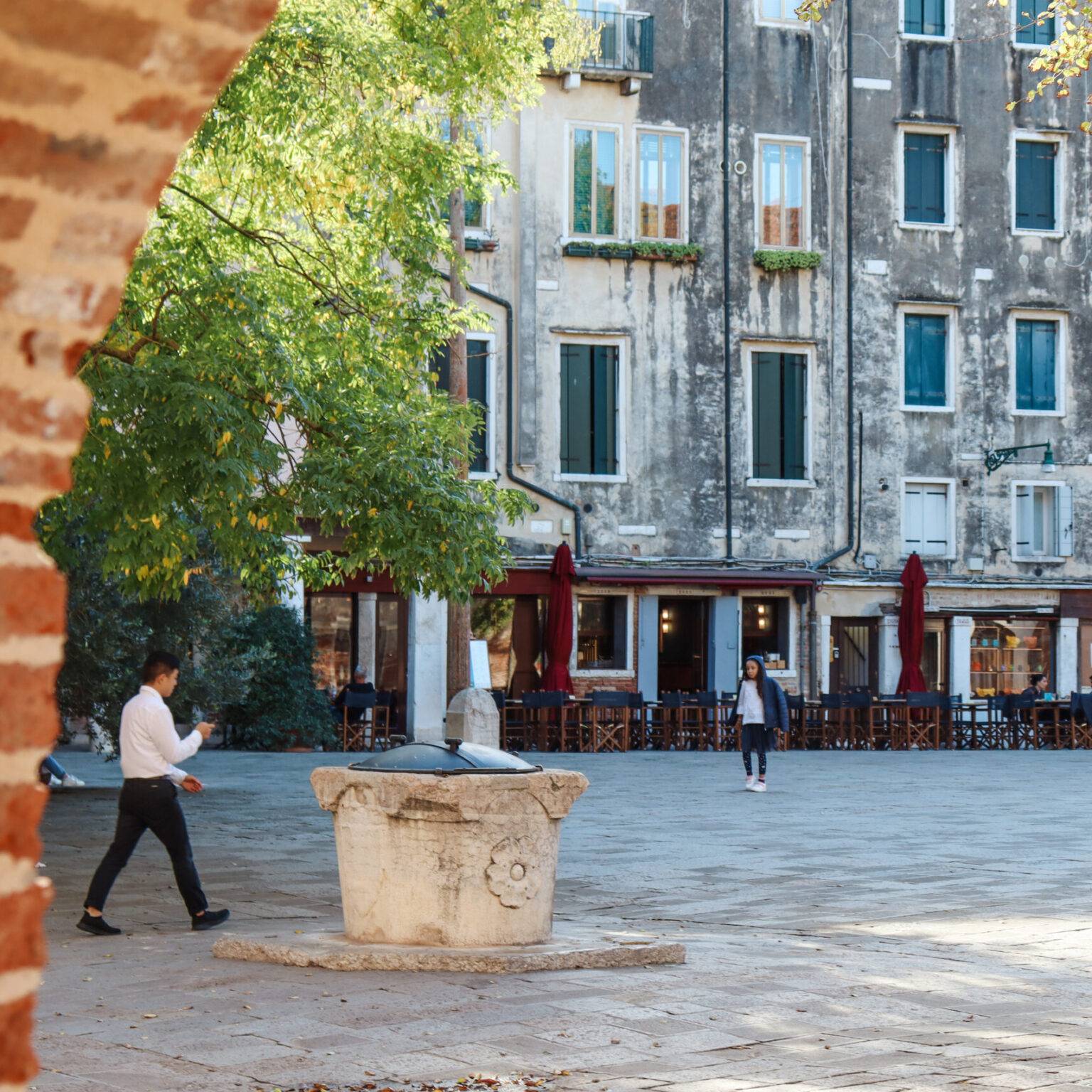 Der Campo di Ghetto Novo, ein gepflasterter Platz, umgeben von Gebäuden. Person laufen darüber.
