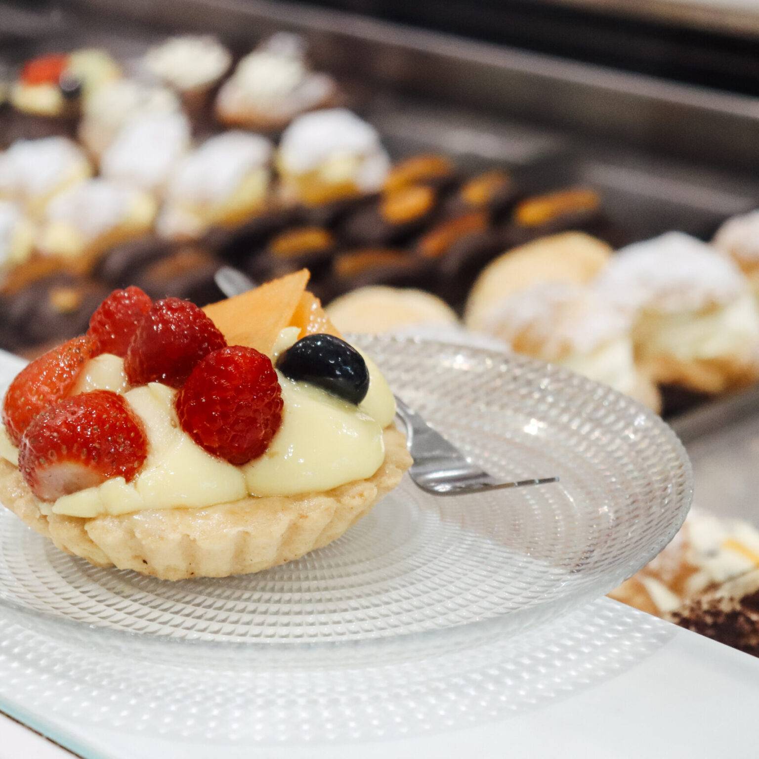 Ein Törtchen mit Vanillecreme und frischen Beeren auf dem Tresen der Pasticceria.