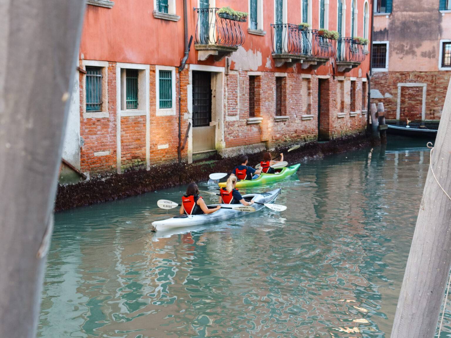 Auf einem Kanal in Venedig sind Kajakfahrer und Kajakfahrerinnen zu sehen.
