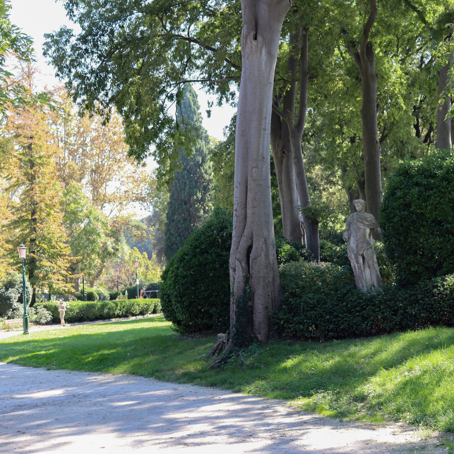 Der Giardini della Biennale: Ein grüner Park mit Kiesweg und Statue.