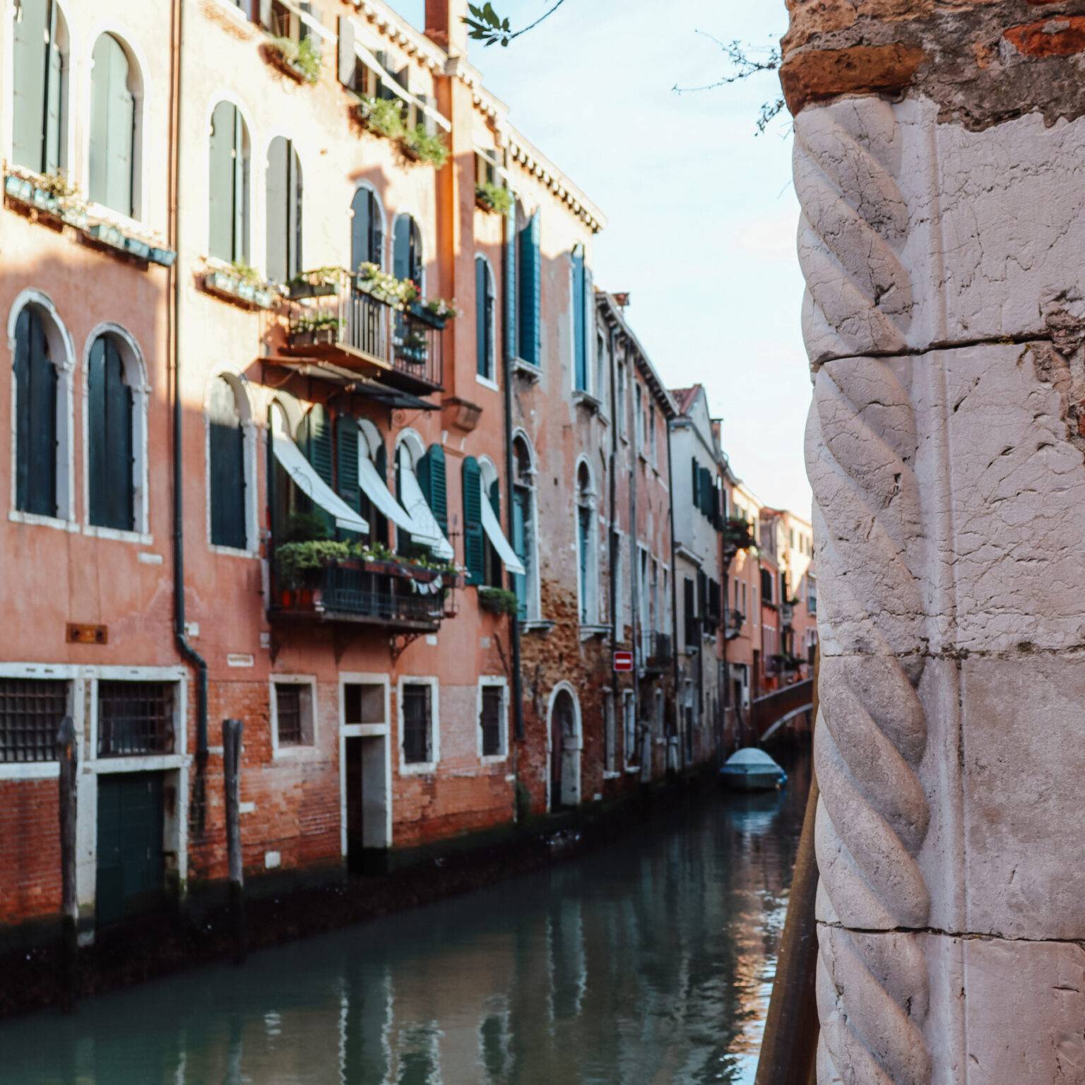 Ein Seitenkanal in Cannaregio mit rosanen Häuserfassaden links.