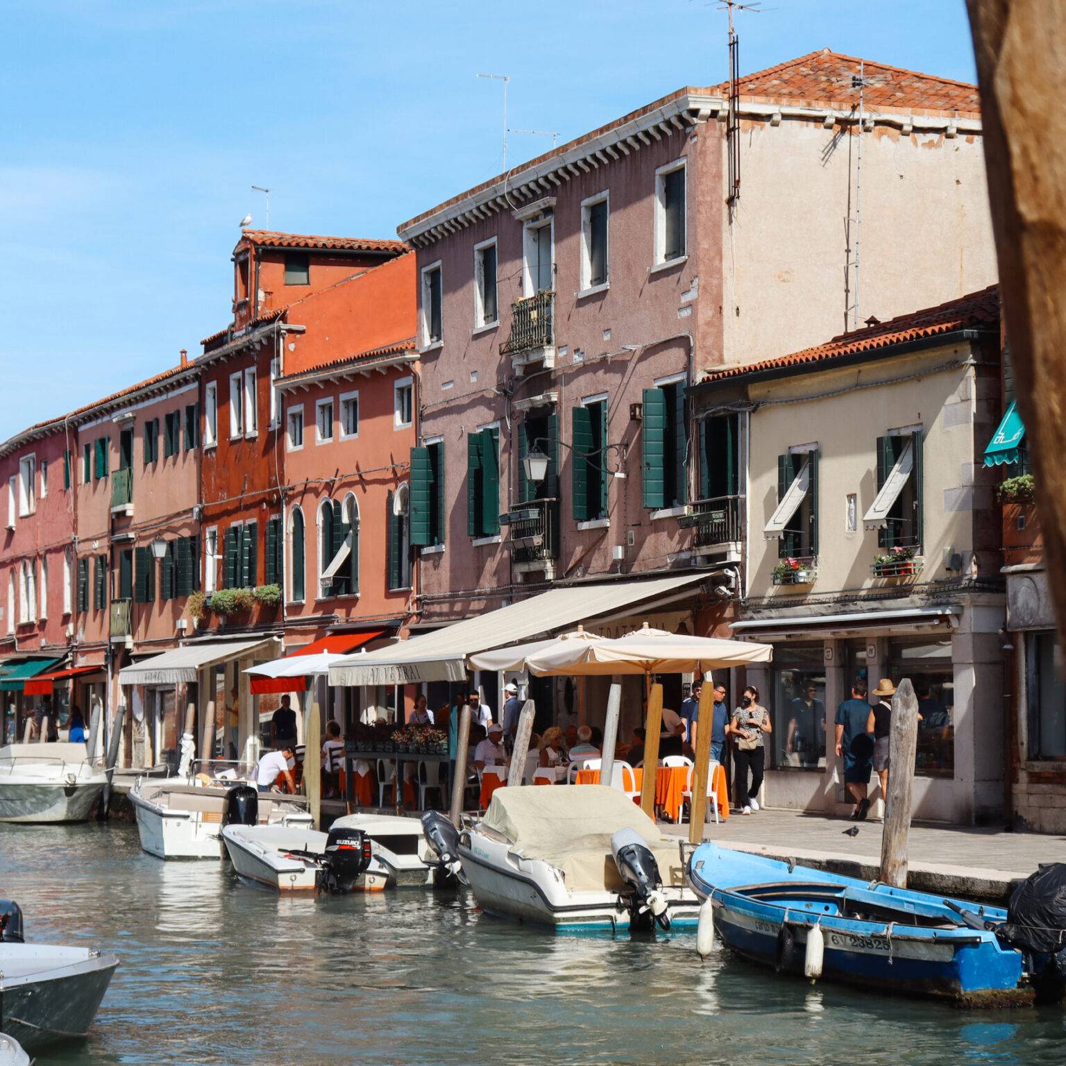 Murano mit kleinen bunten Häuschen und eng geparkten Booten am Kanal.