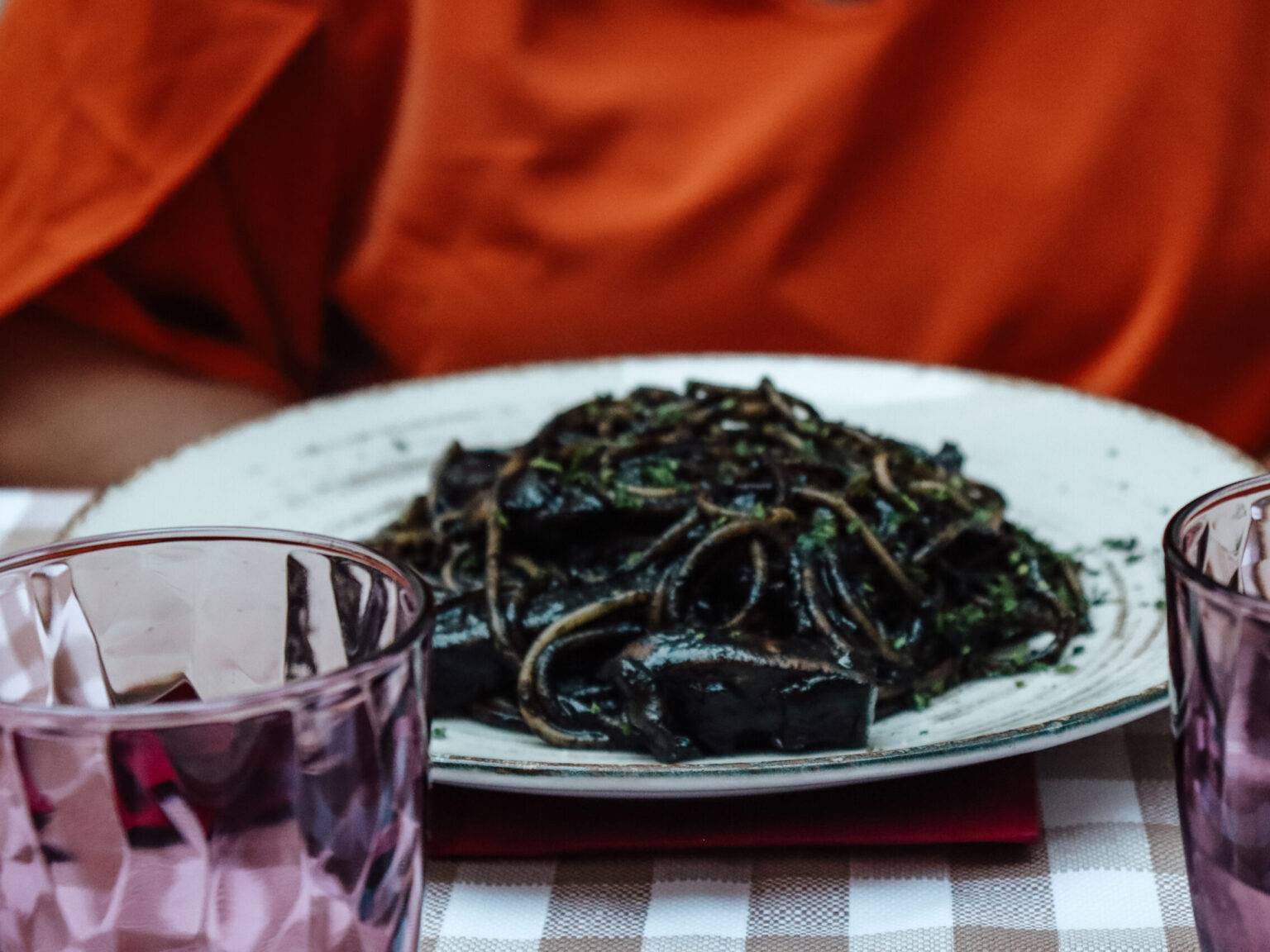 Auf einem Teller das Gericht Spaghetti al Nero di Seppia, Spaghetti in einer schwarzen Soße.