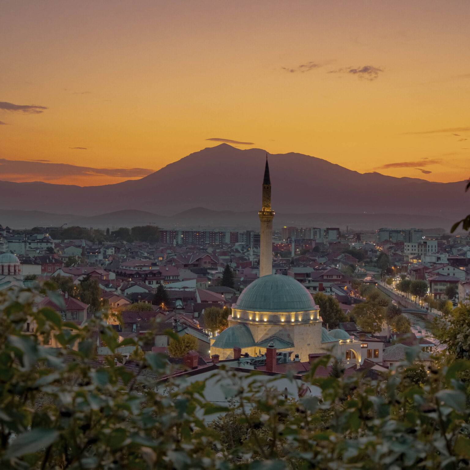Eine Moschee im Zentrum von Prizren im Kosovo ist zum Sonnenuntergang hell erleuchtet.