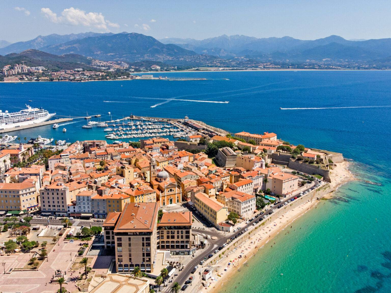 Die kleine Küstenstadt Ajaccio aus der Vogelperspektive umgeben von türkisfarbenem Meer.