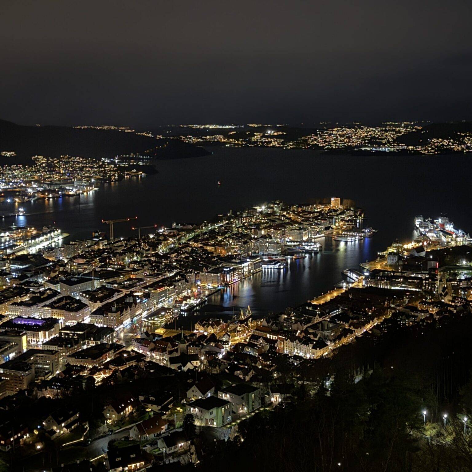 Nachtpanorama von Bergen mit beleuchtetem Hafen und Stadtlichtern, aufgenommen vom Aussichtspunkt auf dem Fløyen.