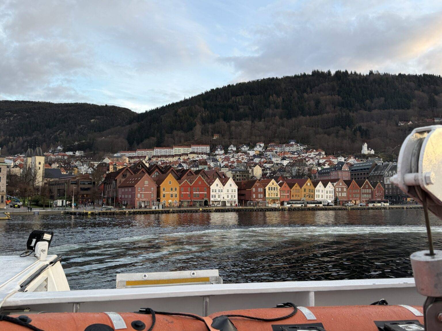 Blick auf die malerische Küste Bergens mit bunten Häusern, umgeben von Bergen und Wasser.