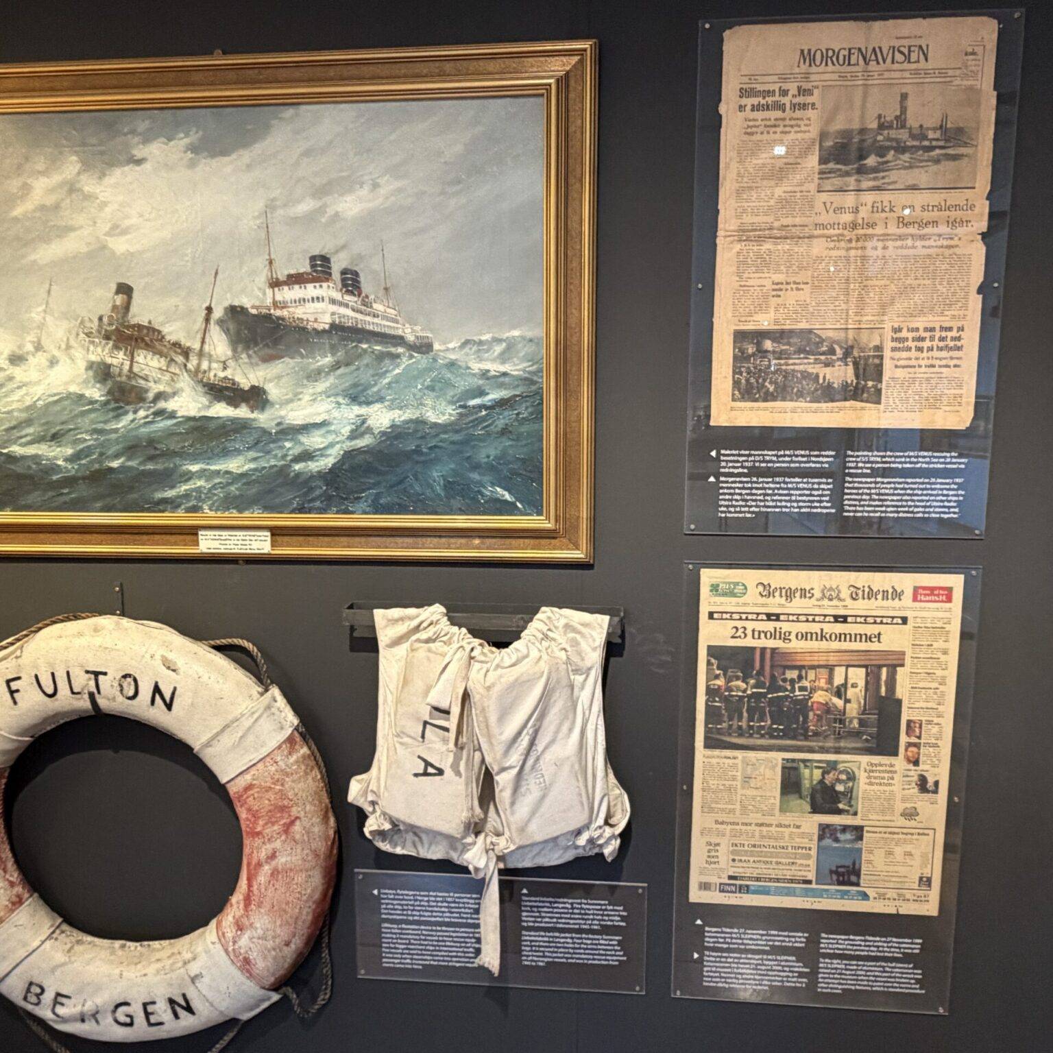 Ein Gemälde eines Schiffs in stürmischer See, umgeben von historischen Dokumenten, einer Rettungsweste und einem Rettungsring.