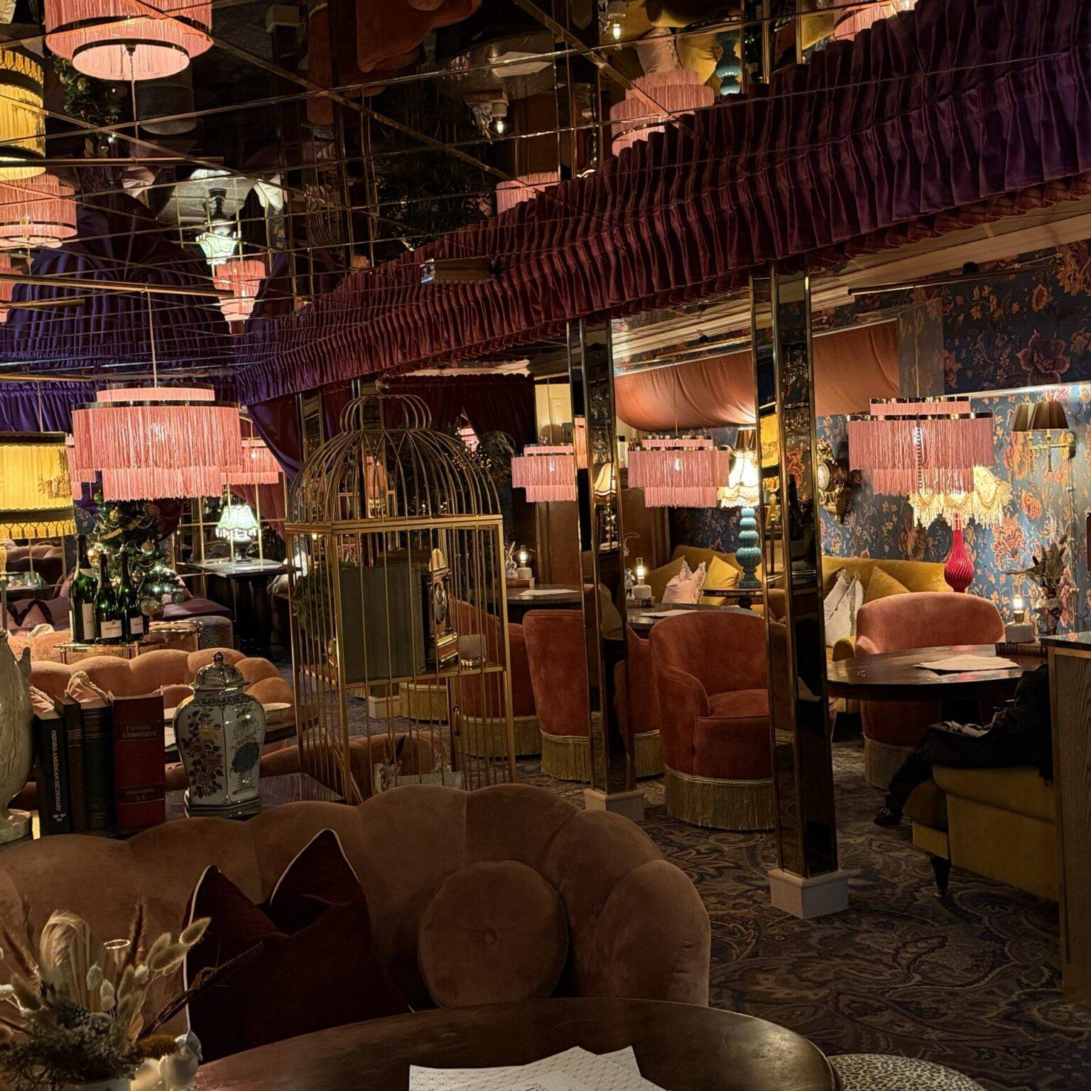 Elegantes Restaurant mit rosafarbenen Deckenlampen, opulenten Möbeln und einem glamourösen Ambiente.