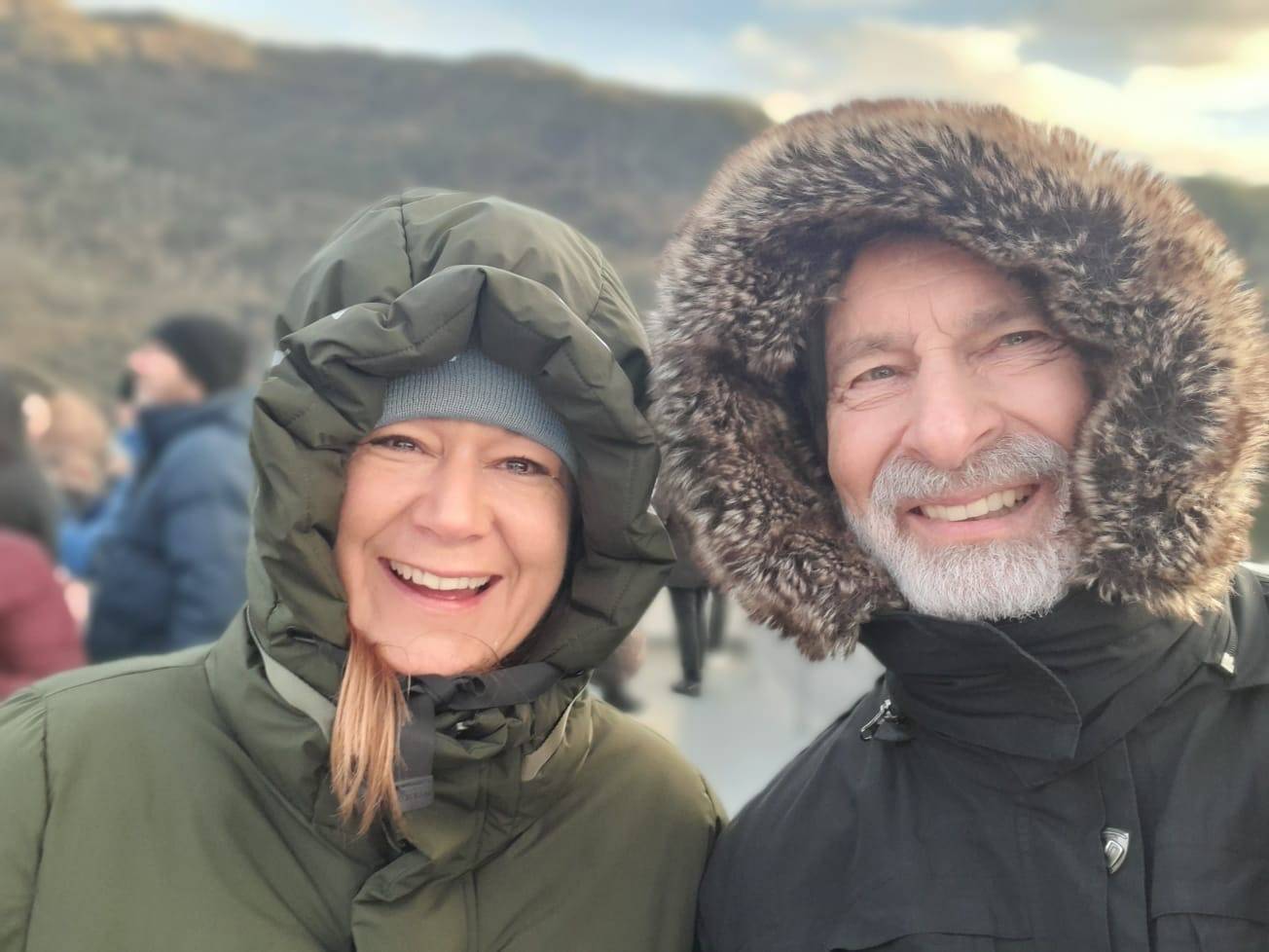 Nahaufnahme von zwei lachenden Personen in warmer Outdoor-Kleidung bei kaltem Wetter.