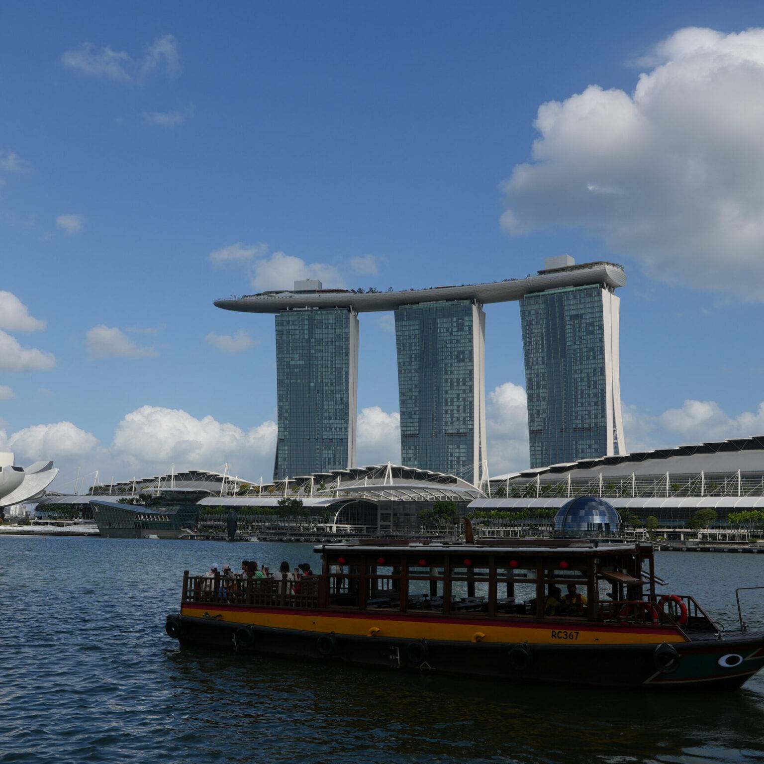 Touristisches Boot fährt am futuristischen Marina Bay Sands Hotel in Singapur vorbei