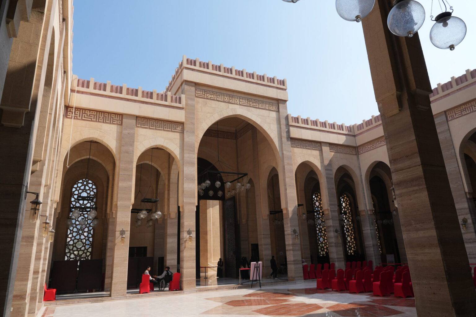 Säulengang im Innenhof der Al Fateh Grand Mosque in Manama, mit kunstvollen Bogenfenstern und Mosaikboden.