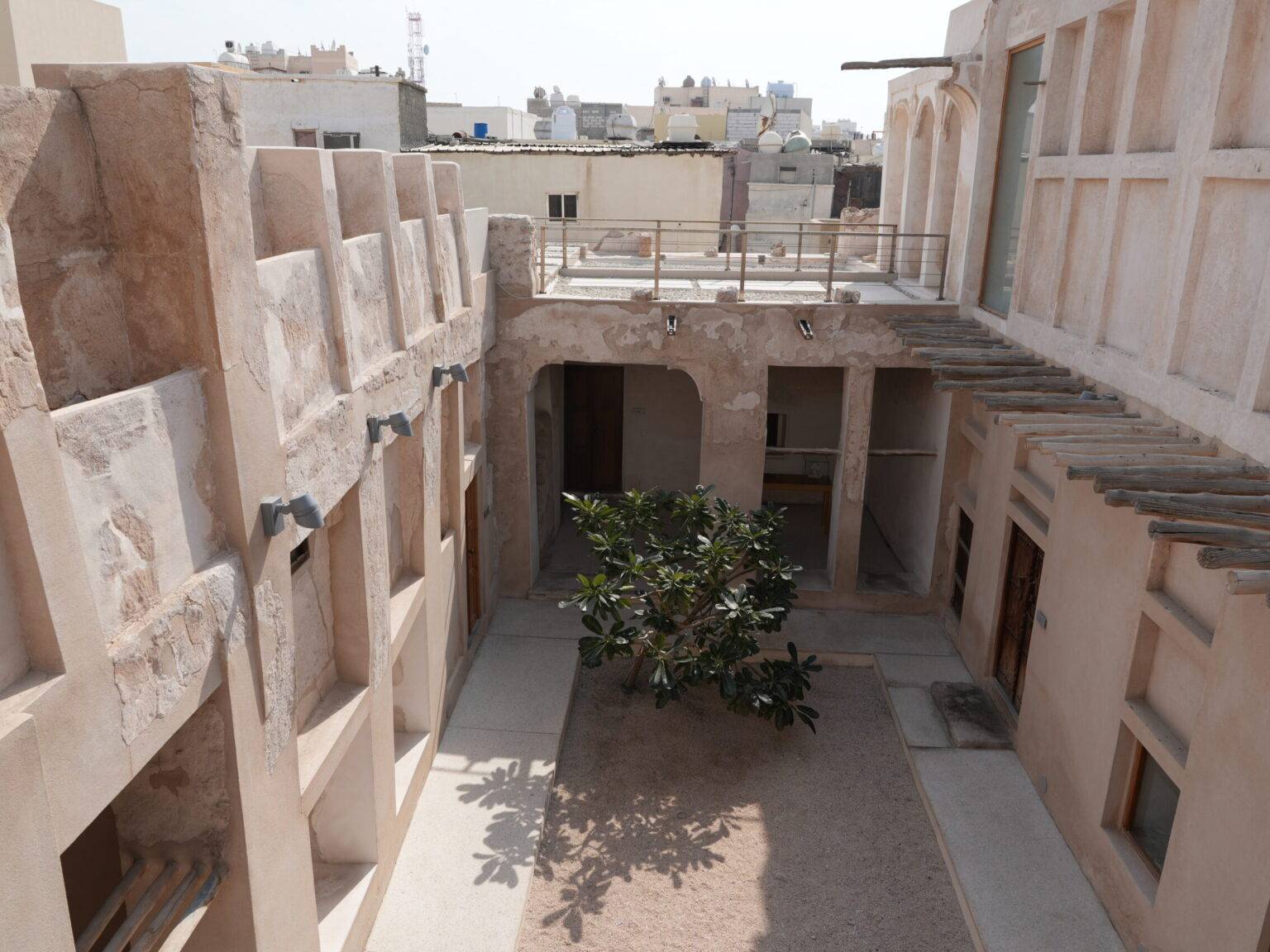 Restaurierter Innenhof eines historischen Kaufmannshauses am Pearling Path in Muharraq, mit alten Steinmauern und einem kleinen Baum in der Mitte.