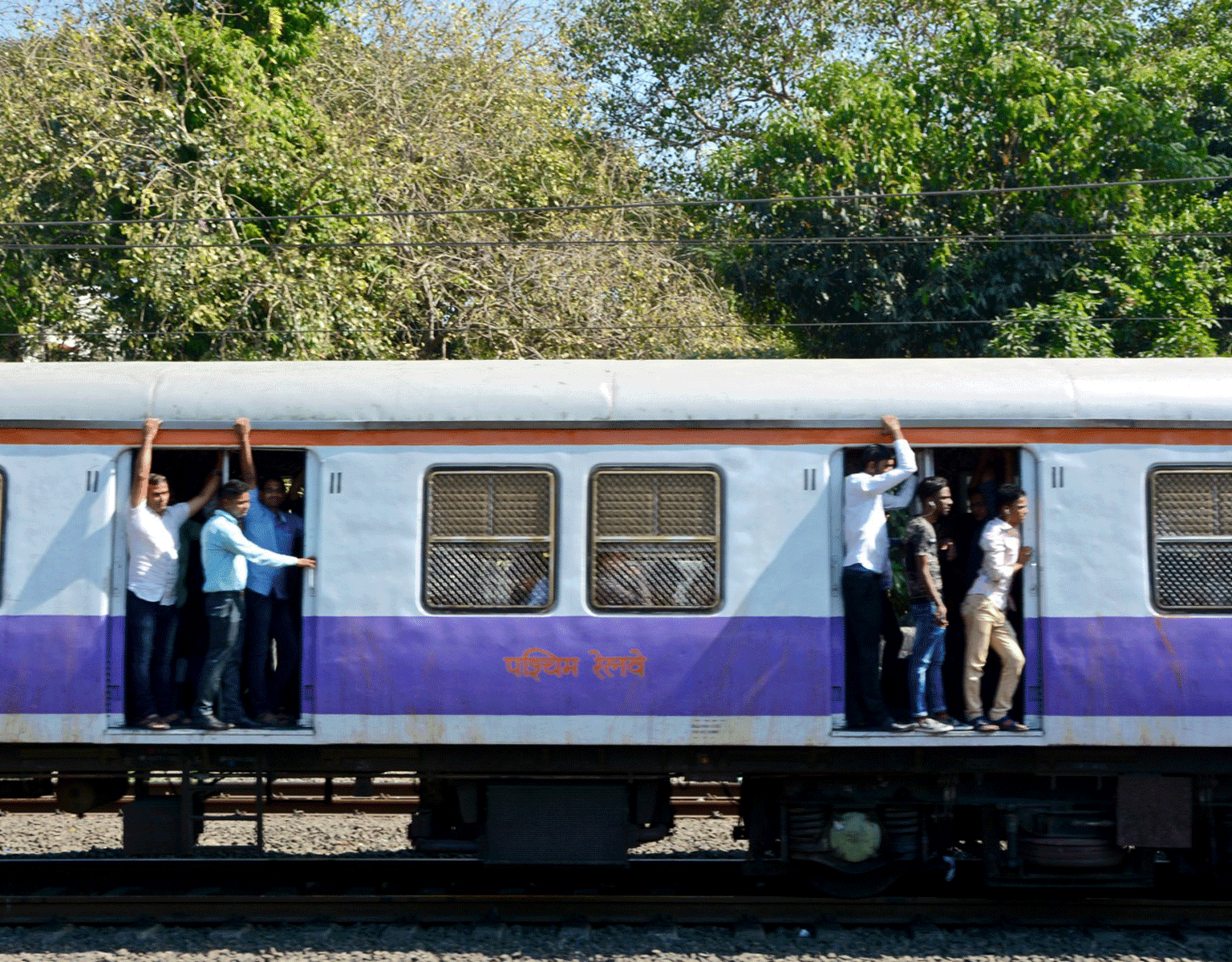 In Mumbai stehen Einheimische in den geöffneten Zugtüren des blau-weißen Western Railways.