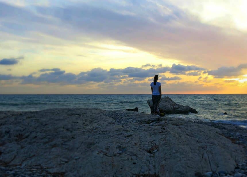 Reisebloggerin Eva genießt am Aphrodite-Strand Petra tou Romiou in Zypern den Sonnenuntergang über dem Meer.