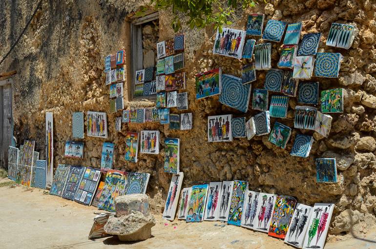 An einer steinigen Hauswand in Tansanias Stonetown werden Kunstbilder zum Verkauf angeboten.