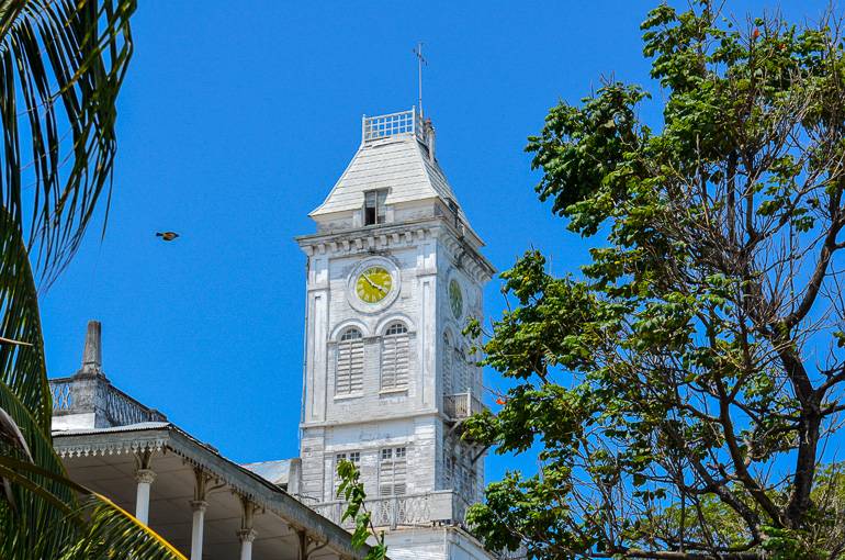 Ein in weiß getünchter Turm mit goldener Uhr in Stonetown auf Tansania zeigt den portugiesischen Einfluss der Stadt.