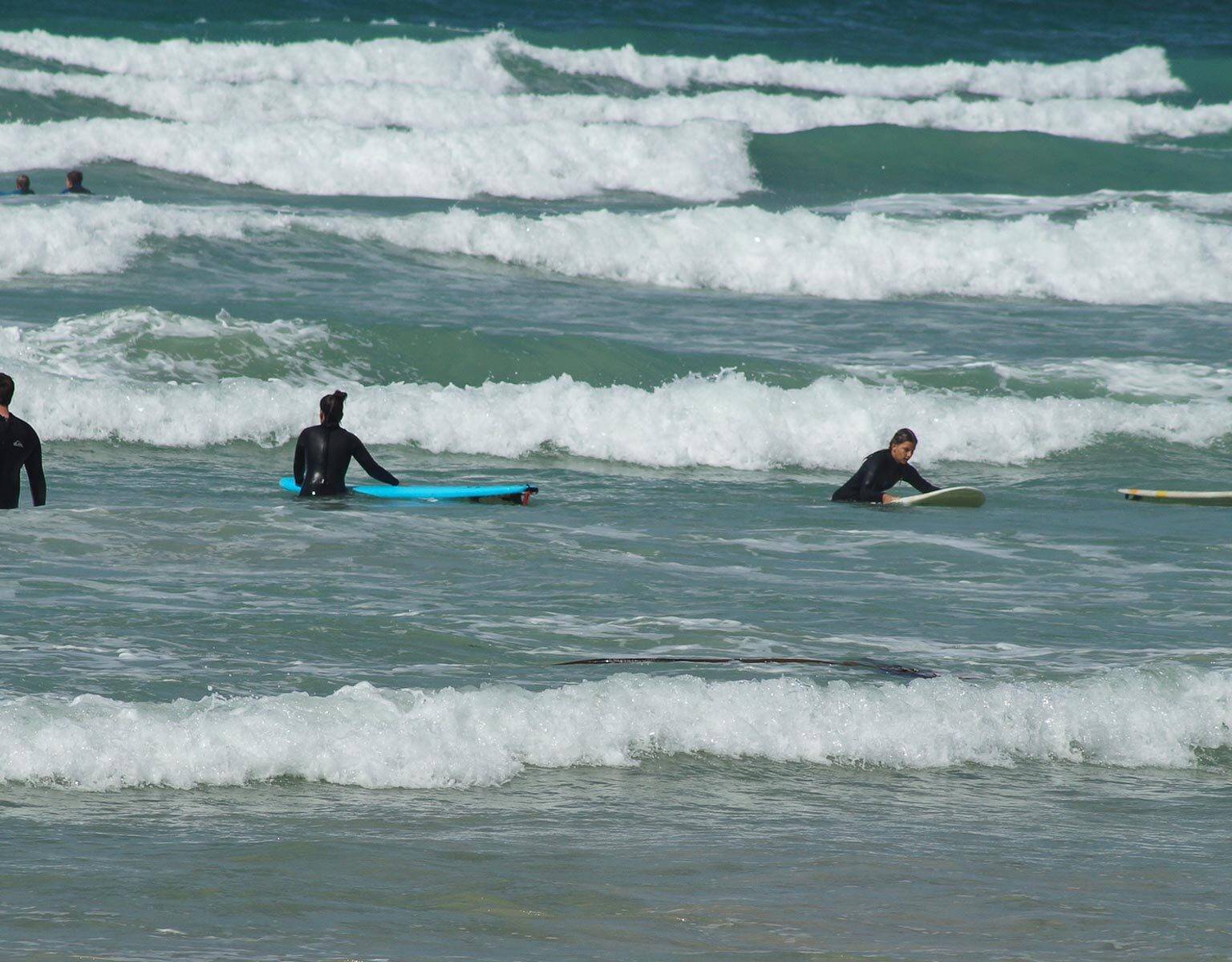 In der Südafrikanischen Kapregion Muizenberg Beach warten vier Surfer im Meer auf eine Welle.