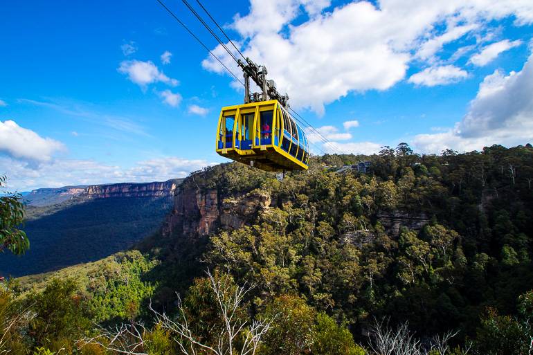 Eine gelbe Gondel des Scenic World Skyway führt über die bewachsene Berglandschaft von Katoomba in Australien.