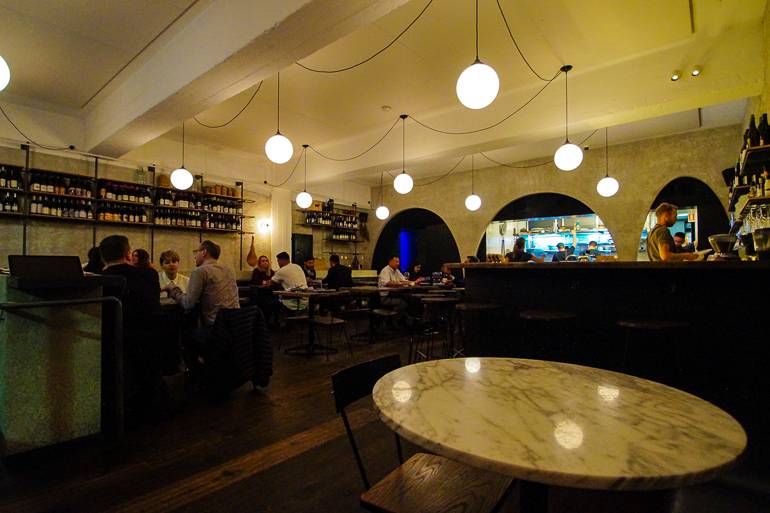 Sydneys Restaurant Ester gewährt Einblick in die Küche hinter weißen Kugellampen, die von der Decke hängen.