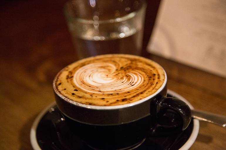 Victoria, Australien: Ein Cappuccino mit einem Milchschaum in Herzform und schwarzer Tasse wird in einem Café in Melbourne serviert.