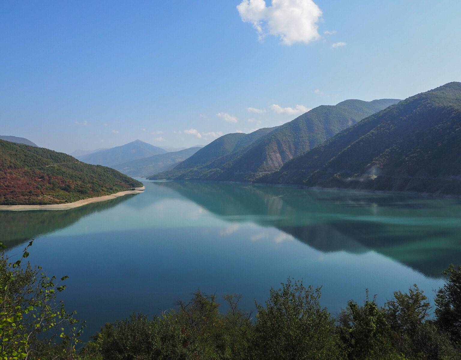 Die tiefblaue Farbe des Jinvali-Stausees begeistert Reisende auf ihrer Route durch Georgien.