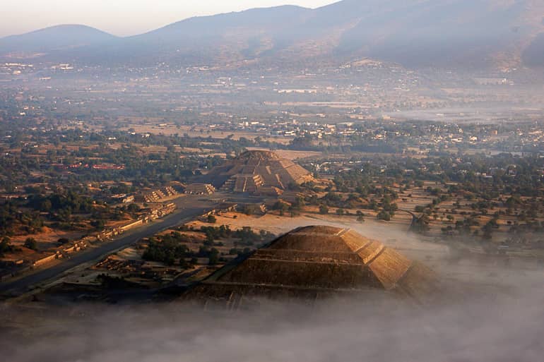 Aus der Vogelperspektive geht die Sonne über den Pyramiden von Mexiko auf und ein leichter Nebel verhüllt den Boden.