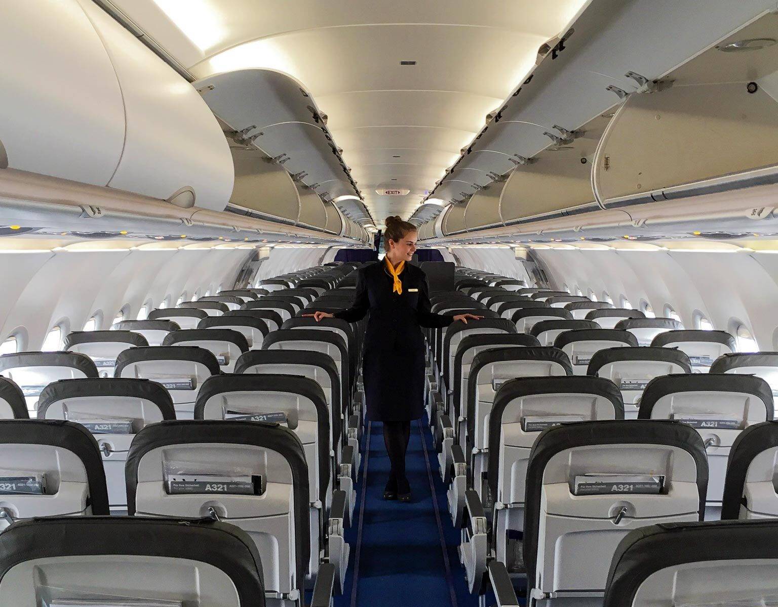 Eine Stewardess geht durch den Flur eines Flugzeuges und überprüft die Sitzreihen.