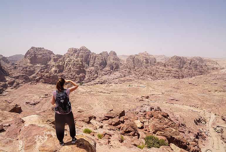 Eine Frau steht auf einem Bergfelsen und blickt auf die Wüste Wadi Araba in Jordanien.