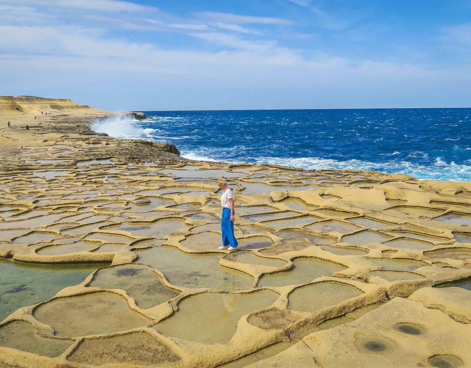 Frau läuft über die mit Meerwasser gefüllten Salzpfannen von Gozo.