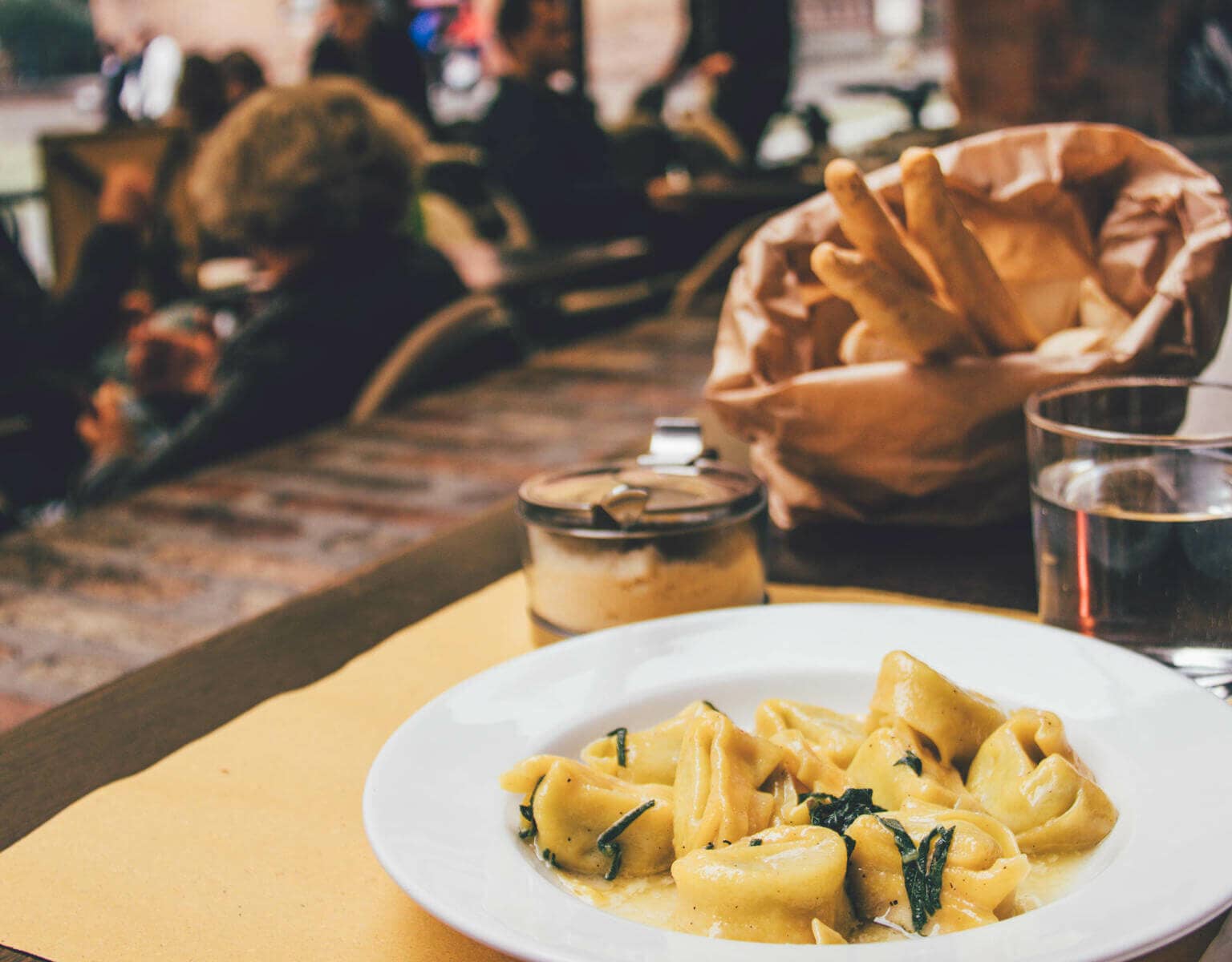 Tipp für Essen in Bologna: Ein angerichteter Teller mit Tortellini auf einem gedecktem Tisch.