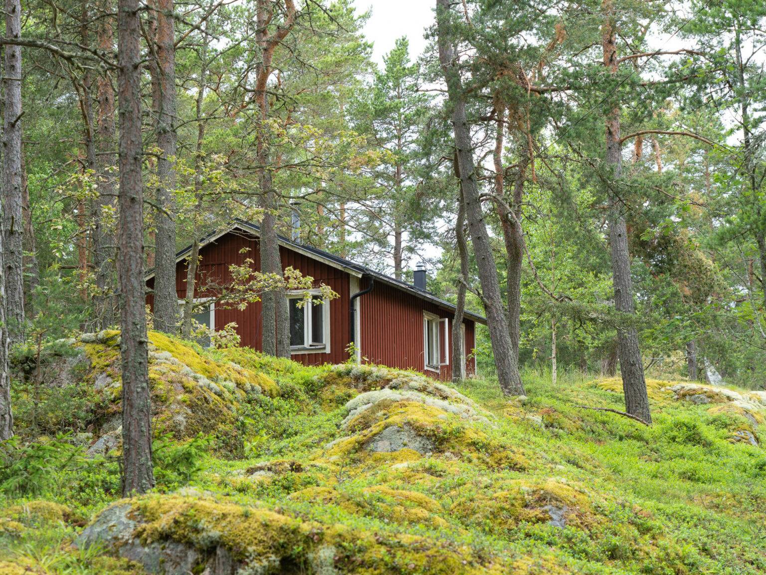 Auf der Insel Grinda stehen kleine rote Holzhäuser als Unterkünfte für die Besucher umgeben von Wald und Wiesen.