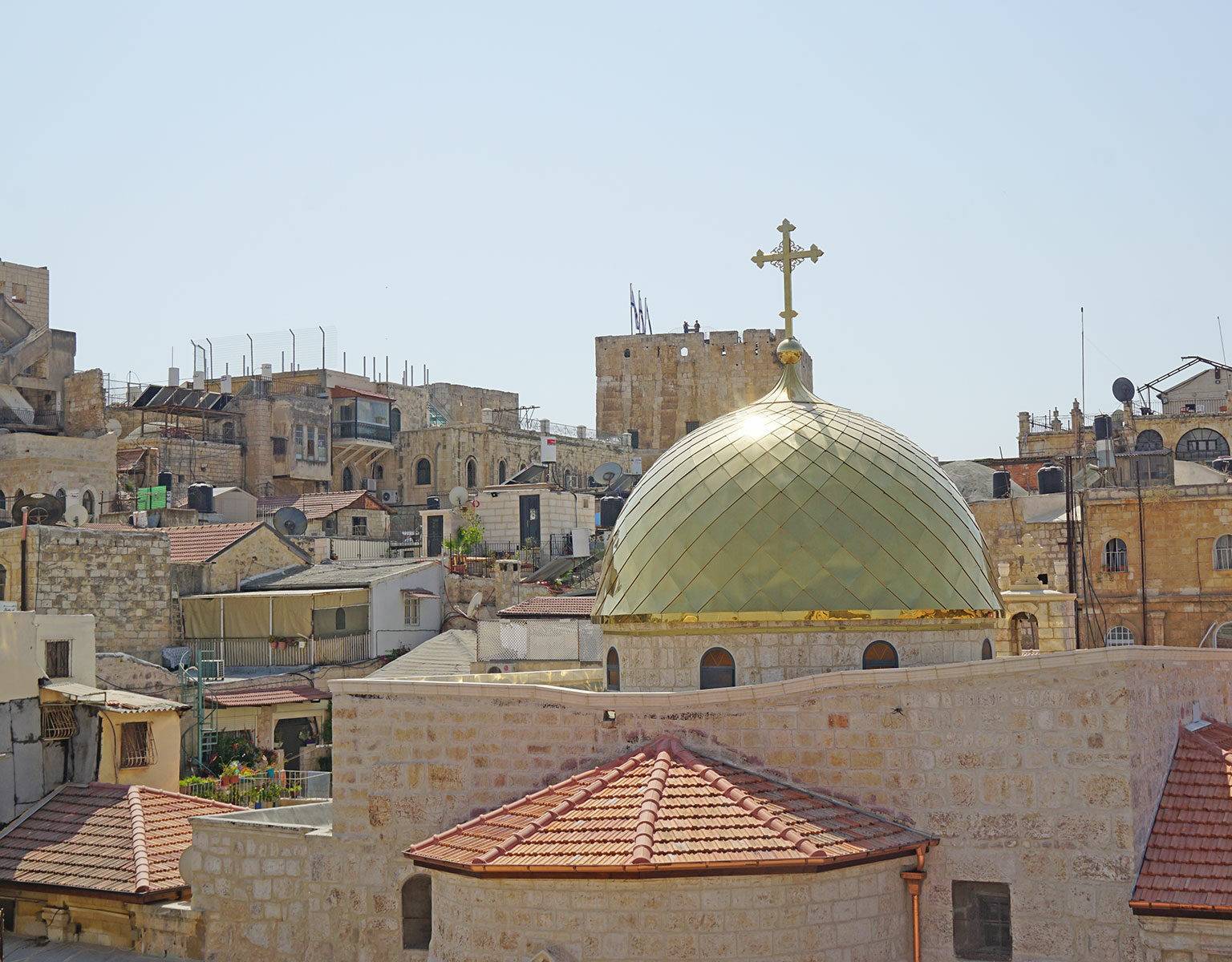 Die Sonne strahlt über den steinernen Gemäuer und einer goldenen Kuppel einer katholischen Kirche in Jerusalem, Israel.