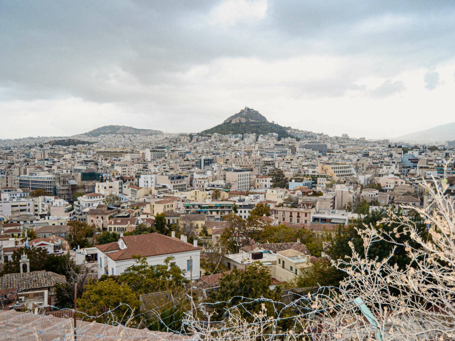 Skyline von Athen, Blick über Häuser und einen Berg i Hintergrund.