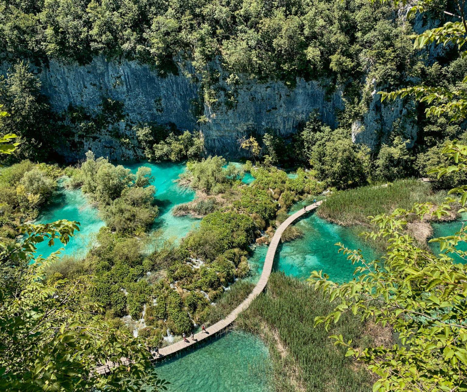 Hölzerne Wanderstege führen Besucher im Nationalpark Plitvicer Seen, Kroatien über das smaragdgrüne Wasser.
