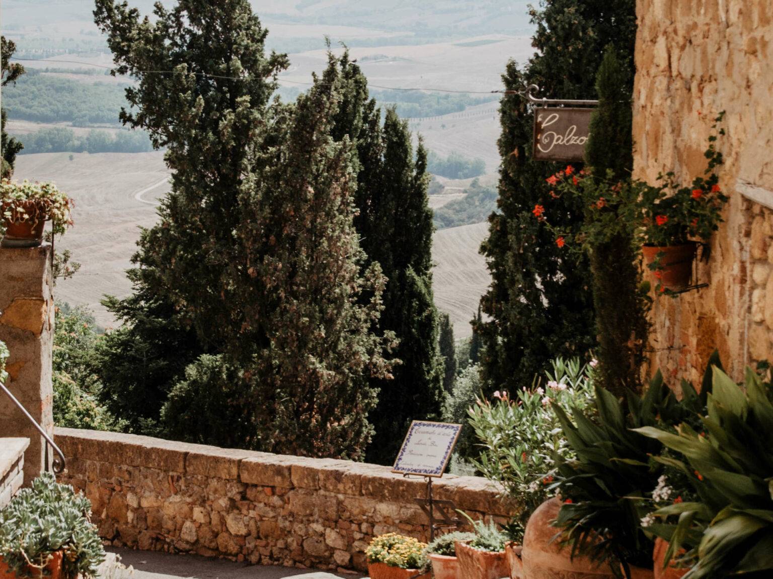 Eine Terrasse mit bepflanzten Blumenkübeln und Aussicht auf die Hügel der Toskana.
