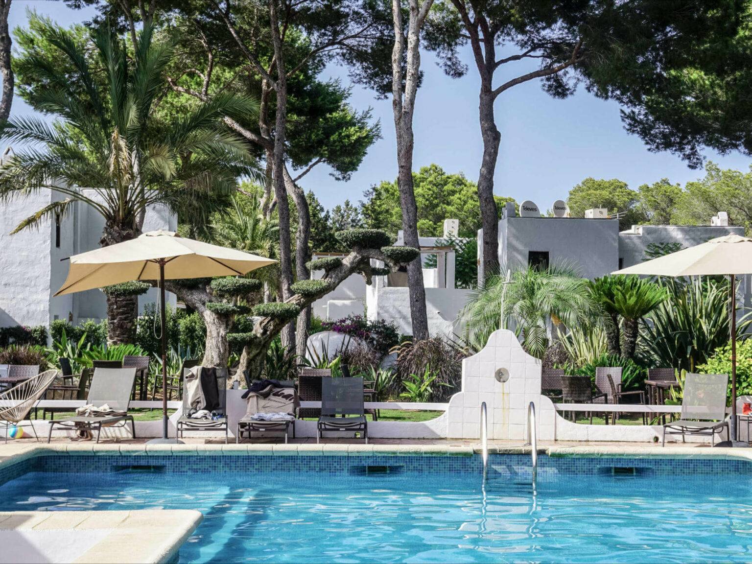 Im Pool der Unterkunft Hotel Casbah auf Formentera kann man zwischen Palmen und weißen Steingebäuden die Seele baumeln lassen.